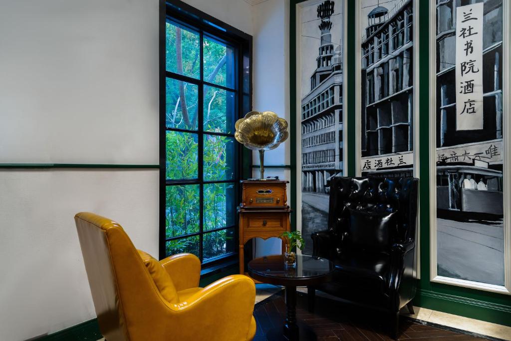 杭州浙大圆正兰社酒店的客厅配有两把椅子、一张桌子和一扇窗户