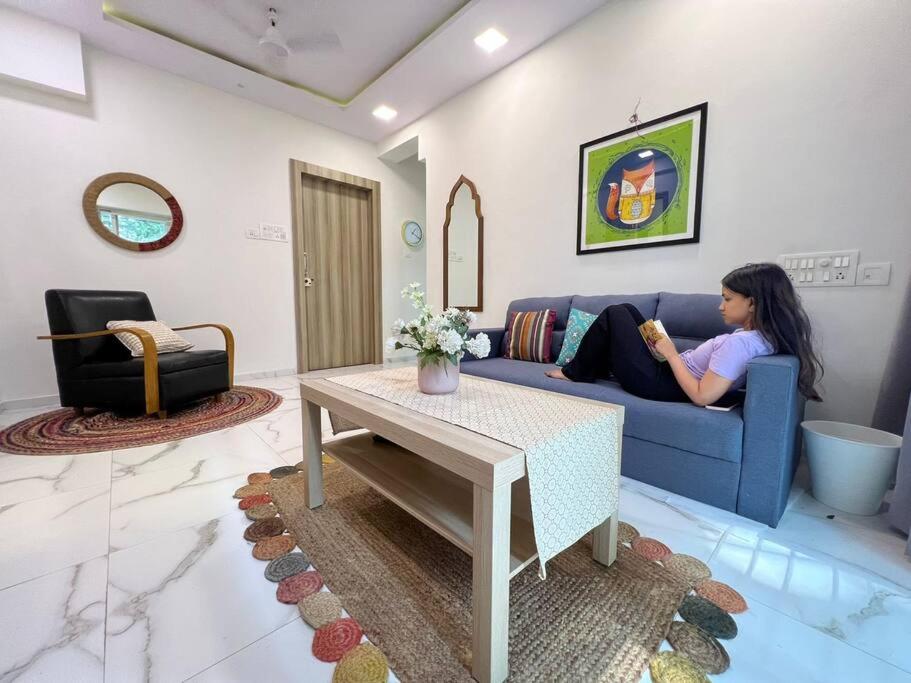 孟买Jastcon, 19th Rd, Khar, Ambedkar Colony by Connekt Homes的坐在客厅蓝色沙发上的女人