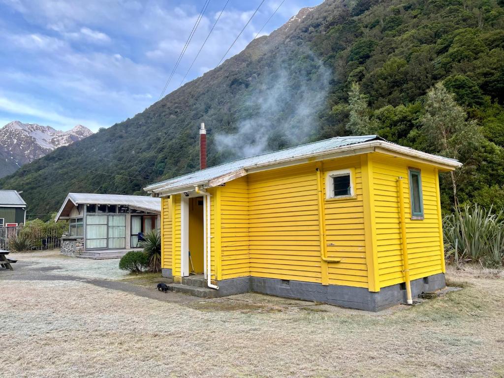 OtiraBasic, Super 'Cosy' Cabin in The Middle of National Park and Mountains的山前的黄色建筑