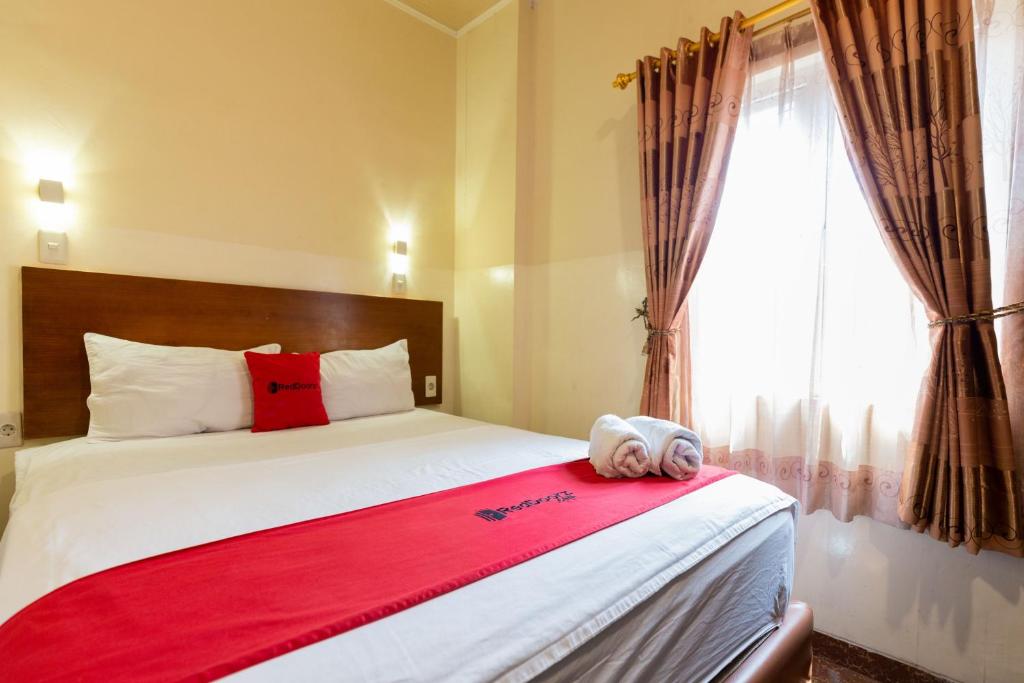 雅加达RedDoorz near Halim Perdanakusuma 3的一间卧室配有一张带红色毯子的床和窗户。