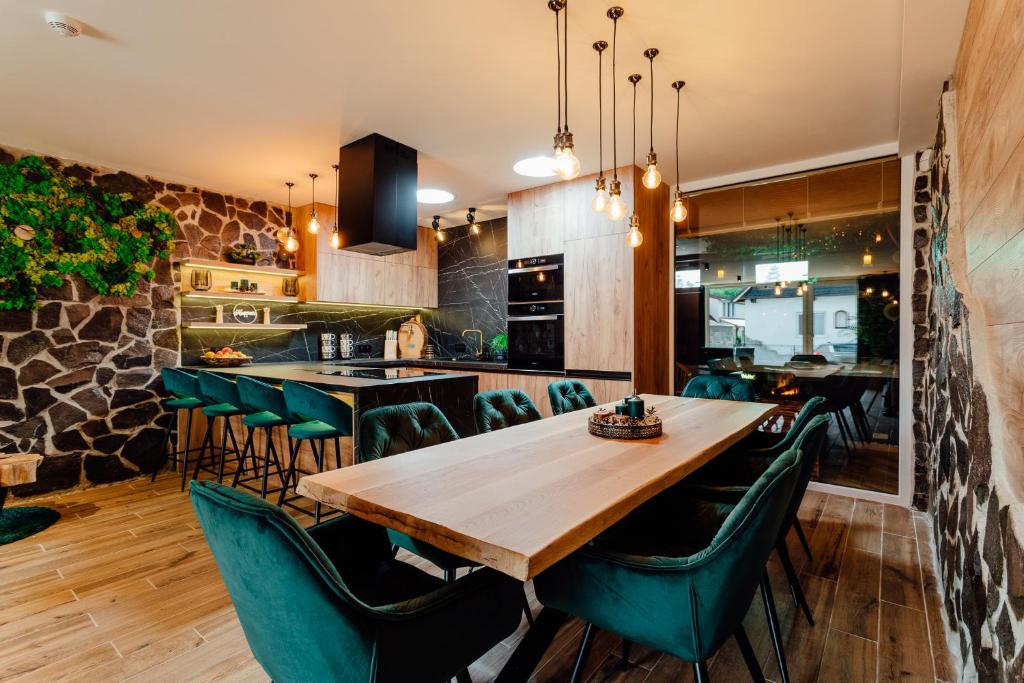 特尔乔夫PARADiSE Wellness Residence的一间带木桌和绿色椅子的用餐室