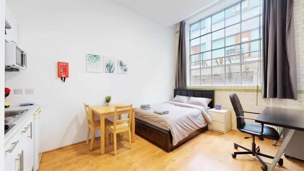 伦敦Amazing Studio Apartment的一间小卧室,配有一张床、一张桌子和一张桌子