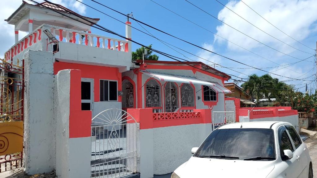 BelfastBeautiful 1-Bedroom in St Thomas Jamaica的停在红色建筑前面的白色汽车