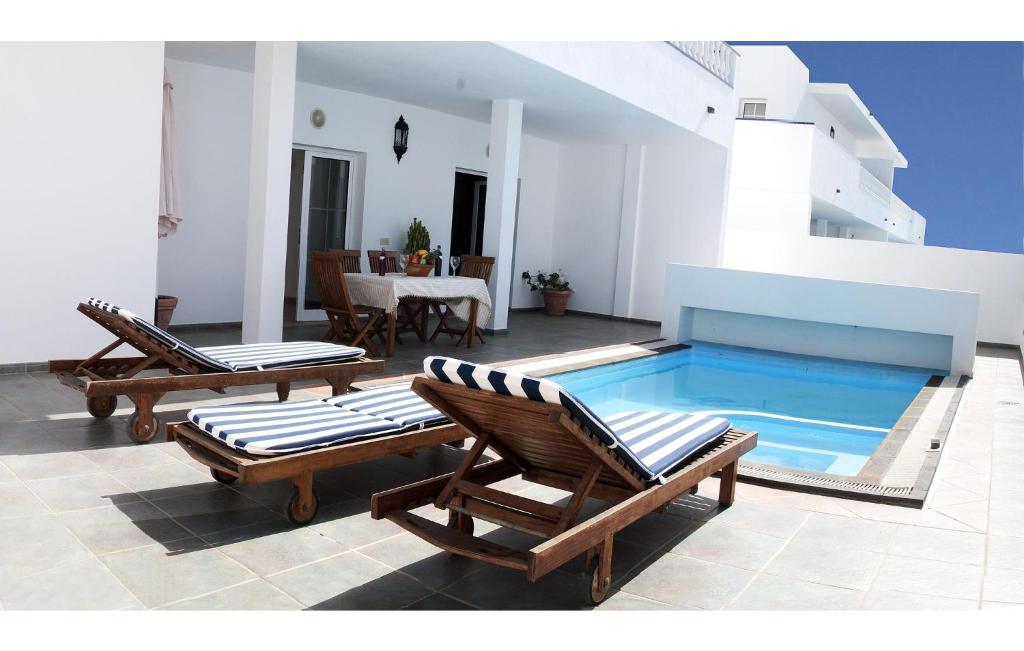 卡列罗港Villas Del Mar的一个带2把躺椅和一张桌子的游泳池