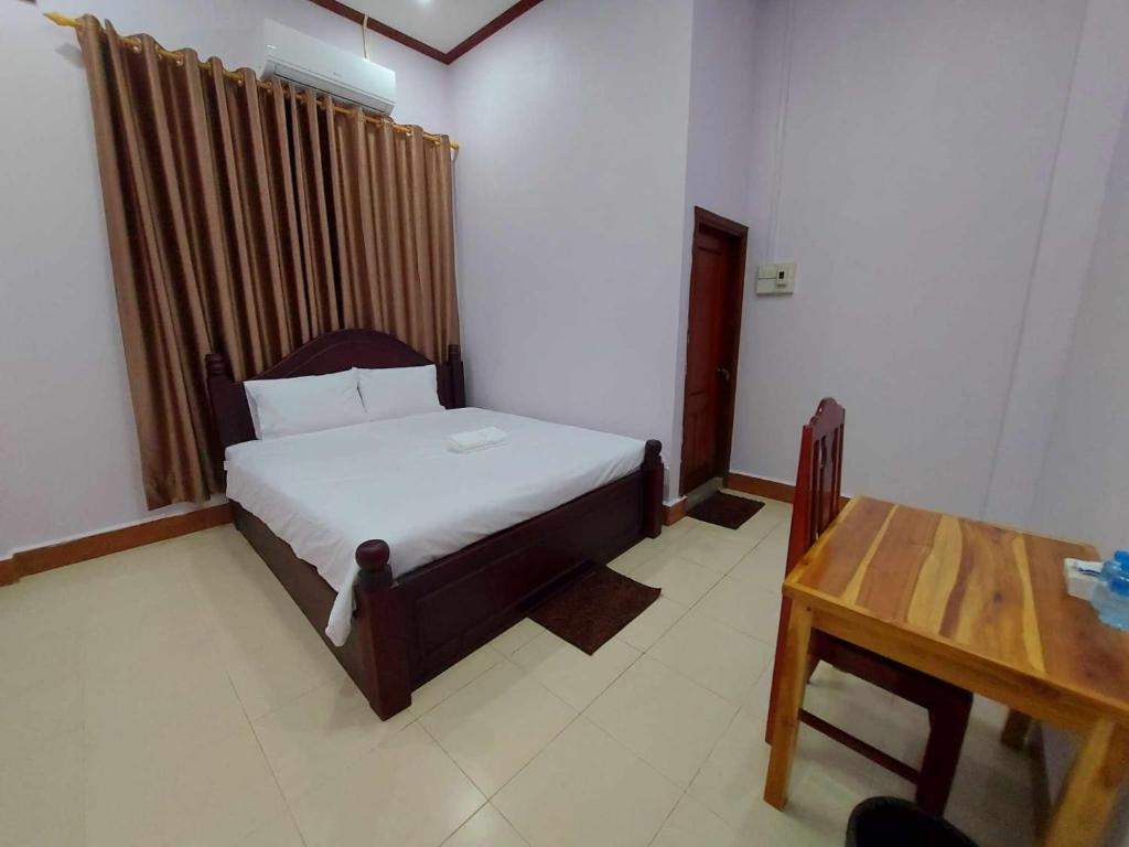 万荣Inthavong Hotel/Guest House的一间卧室配有一张床和一张木桌