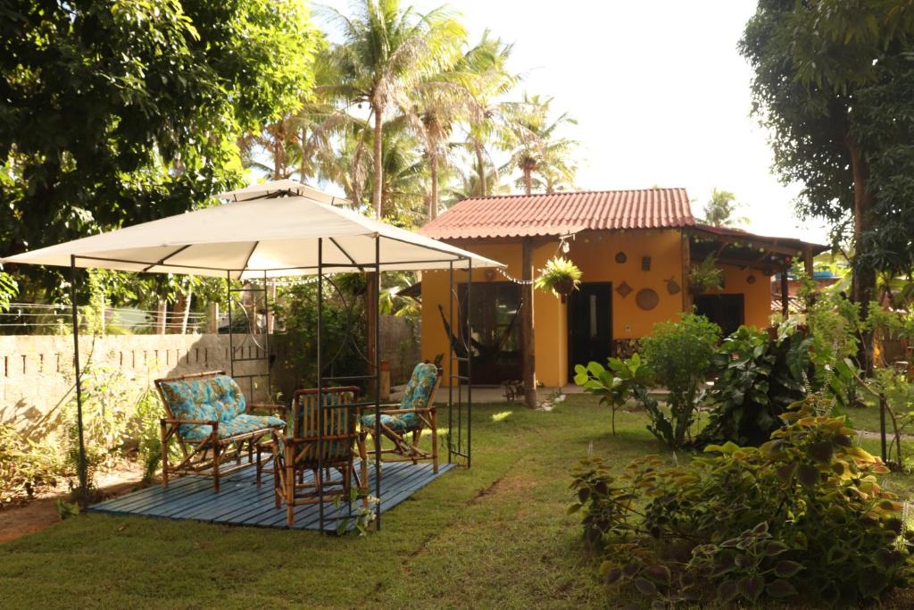 雅帕拉廷加Casa Recanto das Mangueiras Japaratinga - Alagoas的露台配有桌椅和遮阳伞