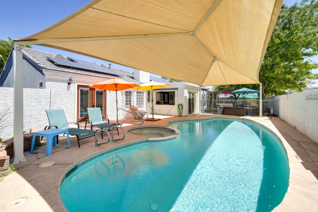 拉斯维加斯Sunny Las Vegas Studio with Shared Pool and Backyard!的一个带遮阳伞和桌椅的游泳池