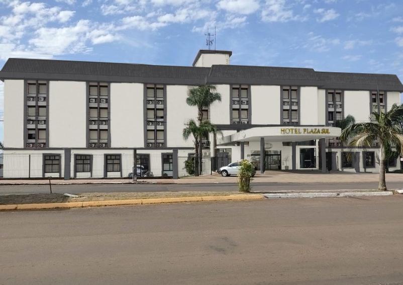 卡拉济纽Hotel Plaza Sul的一座白色的大建筑,前面有棕榈树