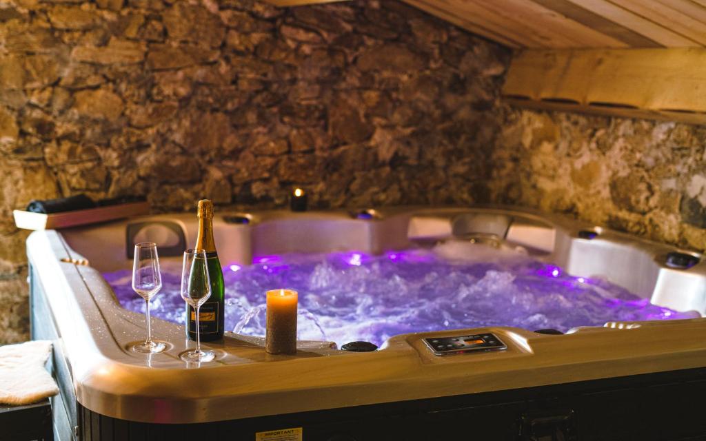 拉纳斯La Ferme de Beauregard SPA -LANARCE 07660 - jacuzzi et sauna的热水浴池,配有1瓶葡萄酒和2杯