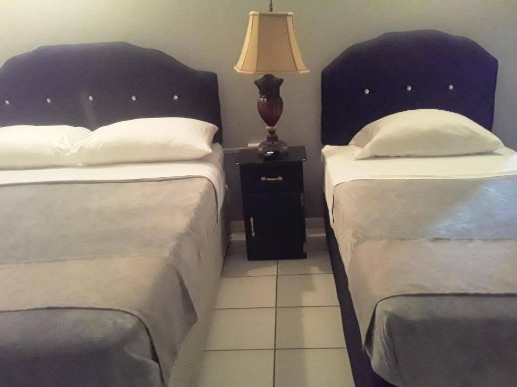 PiarcoDerick's Inn的一间卧室配有两张床和床头灯。