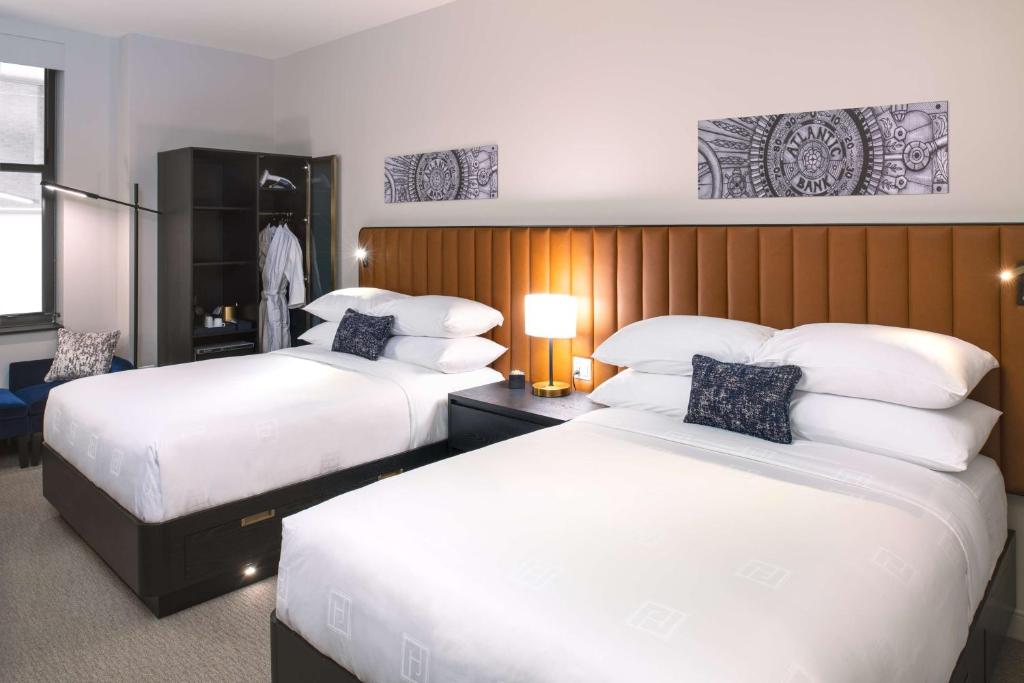 芝加哥Arlo Chicago的配有白色床单的酒店客房内的两张床