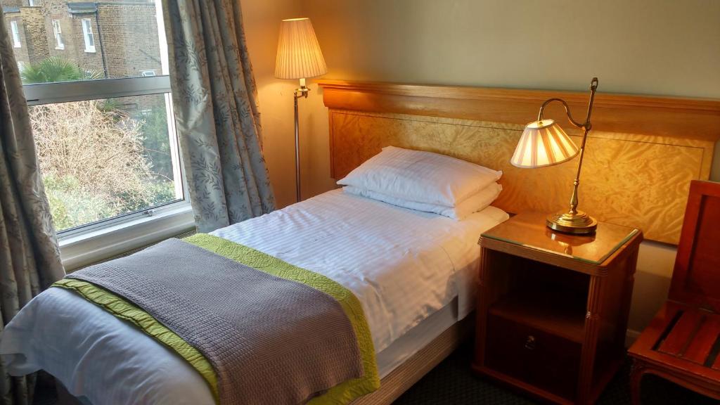 伦敦赛古酒店的一间卧室配有一张带灯和窗户的床