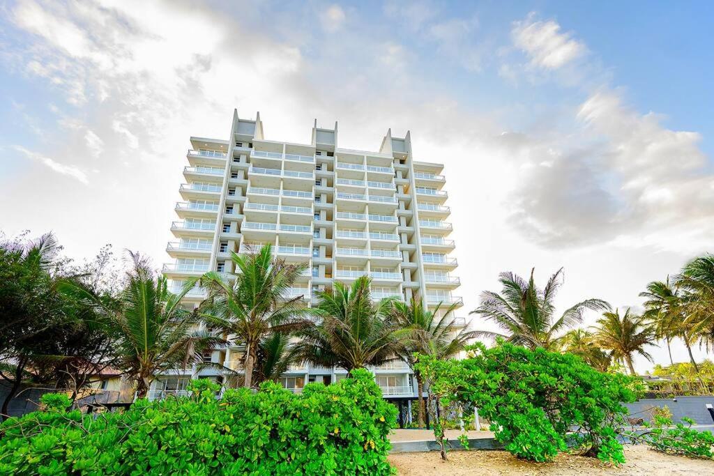 贾埃勒MaSa Beach Front Apartment Uswetakeiyawa的一座白色的大建筑,前面有棕榈树
