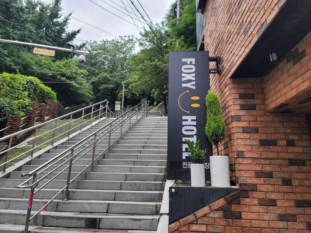 釜山Foxy Hotel的砖砌建筑的一边,有楼梯的标志