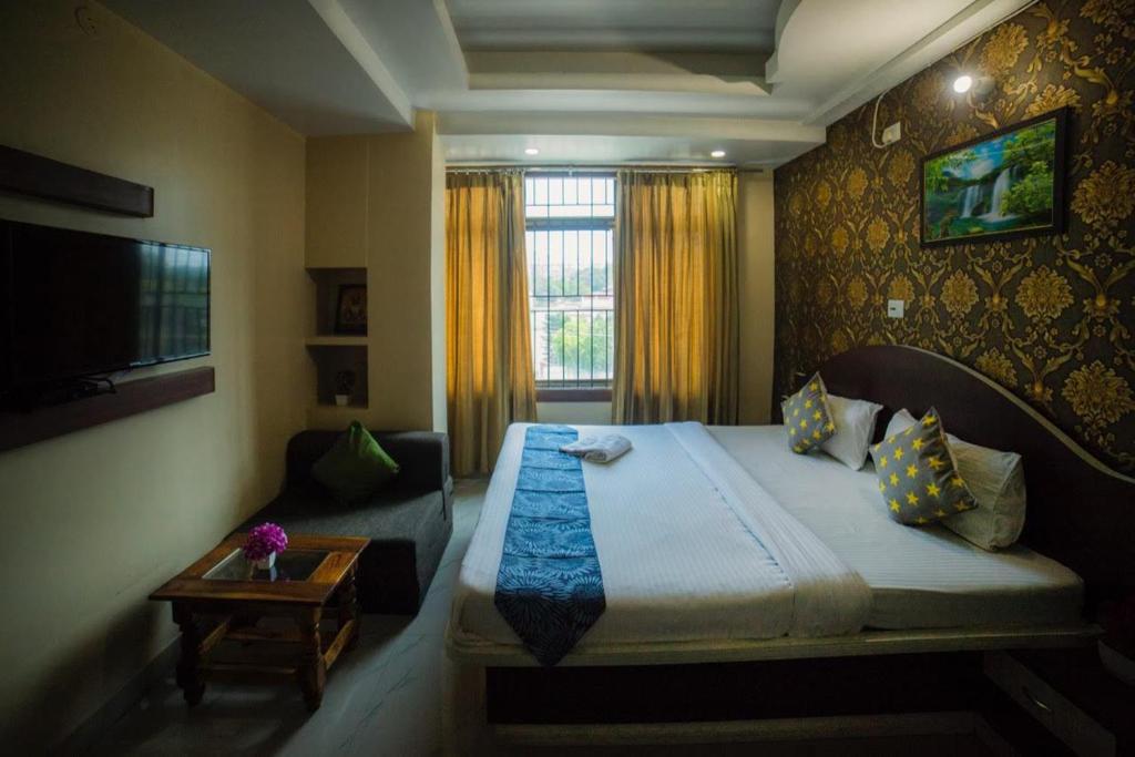 古瓦哈提Asian Suites Guwahati的一间卧室配有一张大床和一张沙发