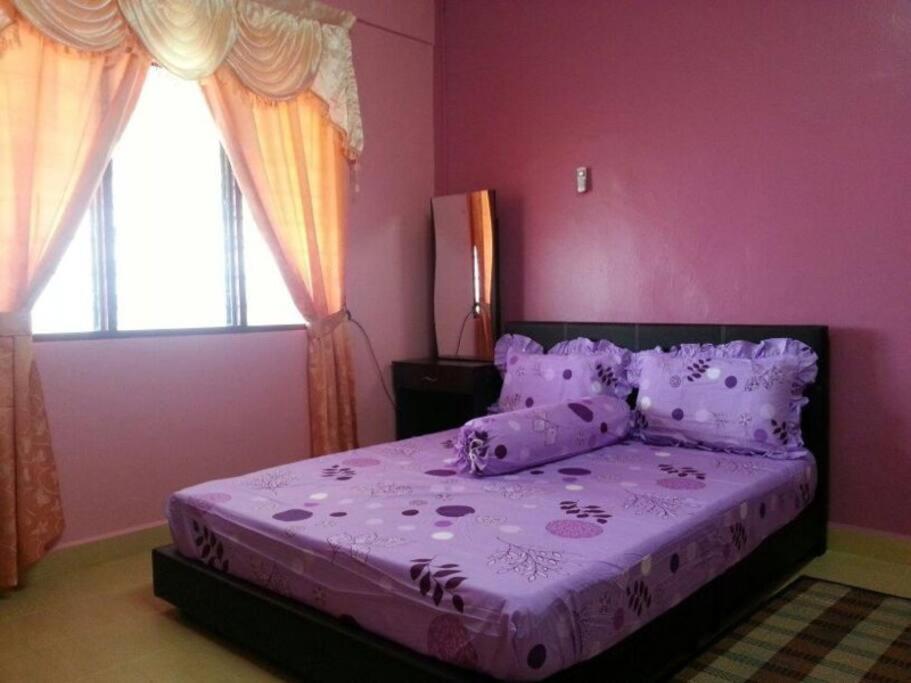 CukaiD'FIEZA HOMESTAY KEMAMAN的粉红色的卧室配有一张带紫色床单和枕头的床