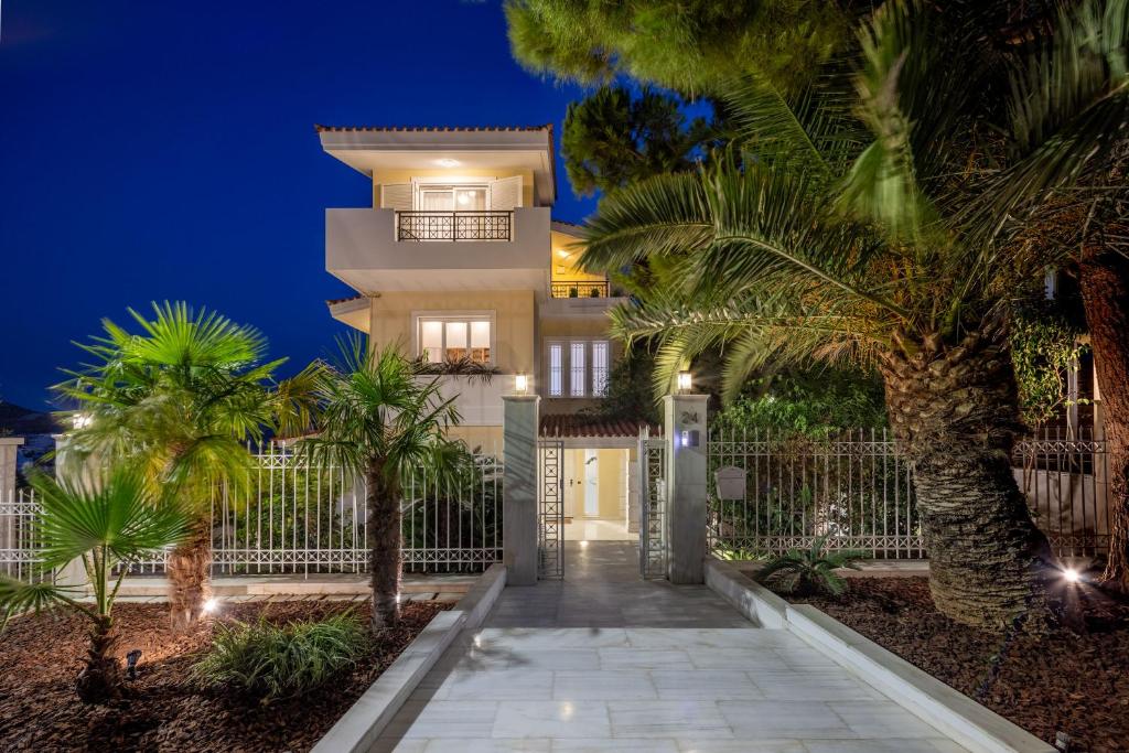 雅典The Southern Mansion Athens的一座别墅,在晚上有门和棕榈树