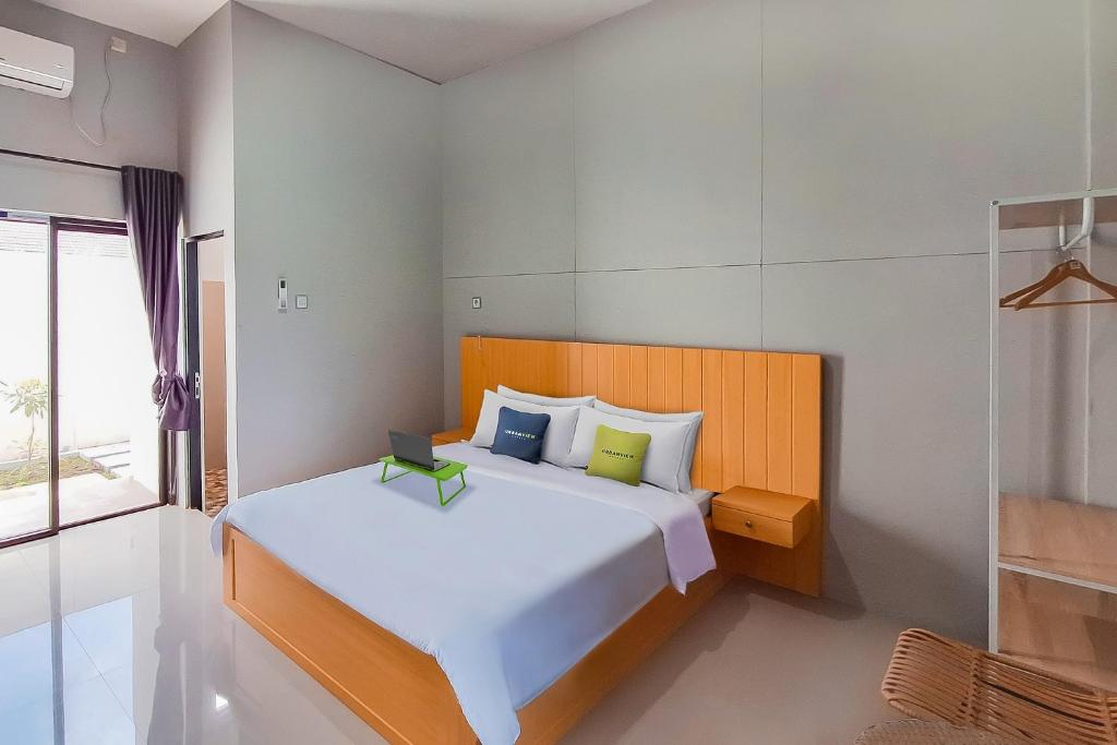 TumbangrunganUrbanview Hotel Griya Menteng Palangkaraya by RedDoorz的卧室设有一张白色大床和一扇窗户。