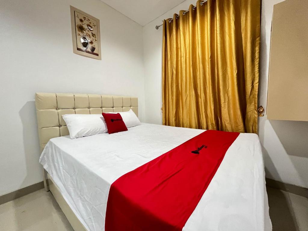 PanikiRedDoorz at Ring Road II Area Manado的卧室配有红色和白色的床,设有窗户