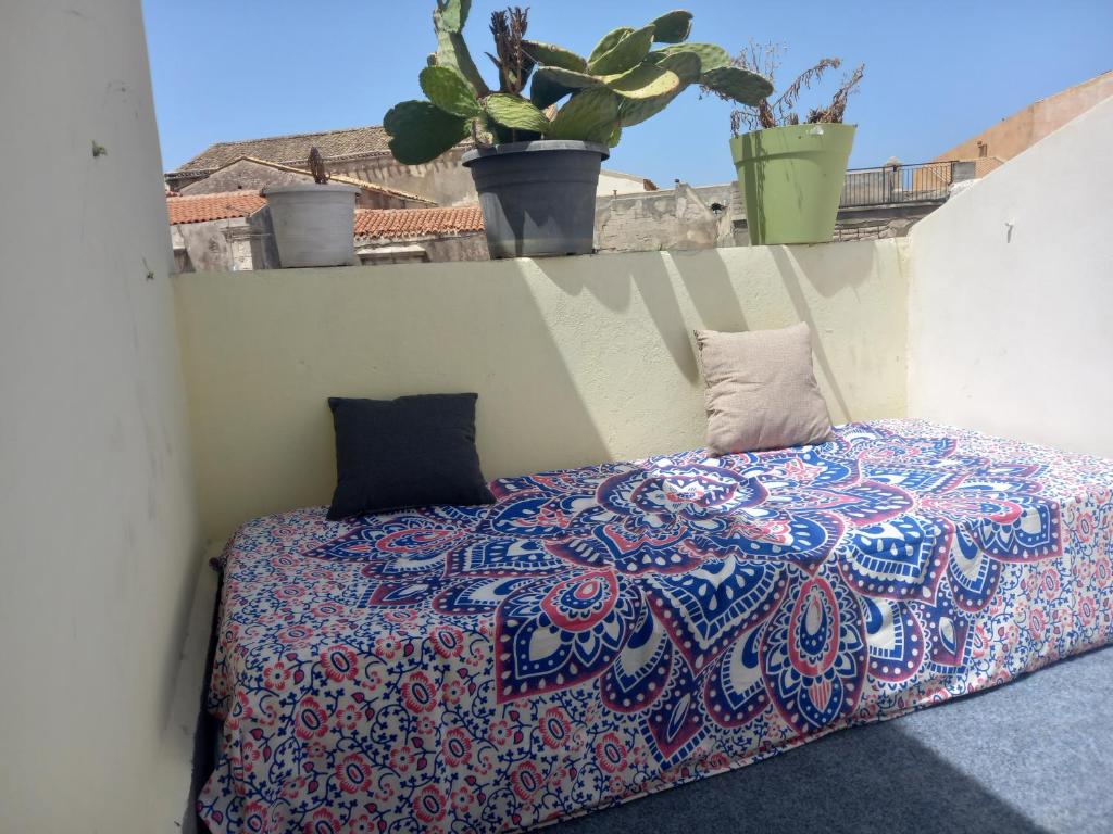 锡拉库扎Casa dei fiori的阳台植物间的一个床位