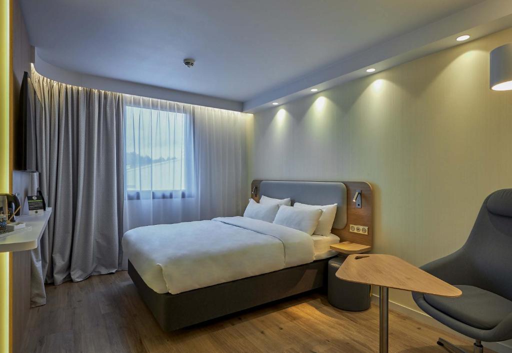多维尔B&B HOTEL Deauville-Touques的配有一张床和一把椅子的酒店客房