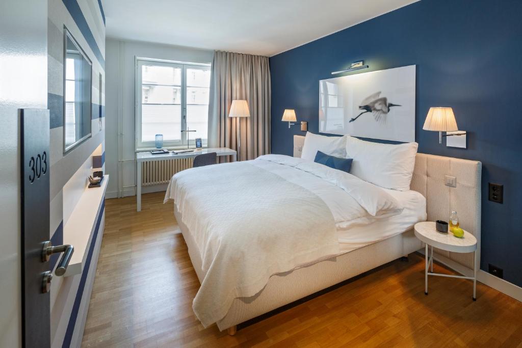 苏黎世西霍夫酒店的一间卧室设有一张大床和蓝色的墙壁