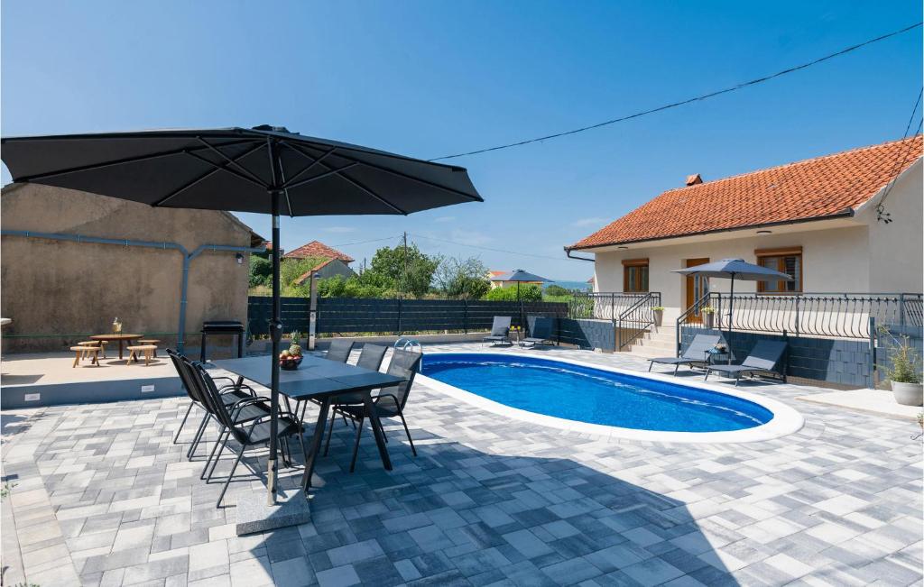 RunovićGorgeous Home In Runovici With Kitchen的一个带桌子和遮阳伞的庭院,毗邻一个游泳池