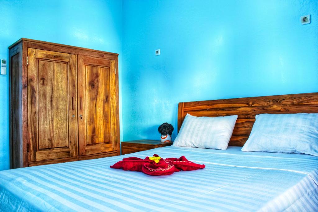 圣吉吉KJ Purple Gate SENGGIGI的蓝色卧室,配有红色衣服的床