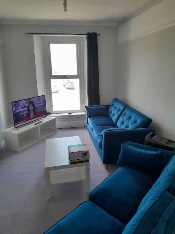 彭布罗克郡Conveniently located, newly refurbished flat (sleeps 4)的客厅配有蓝色的沙发和电视