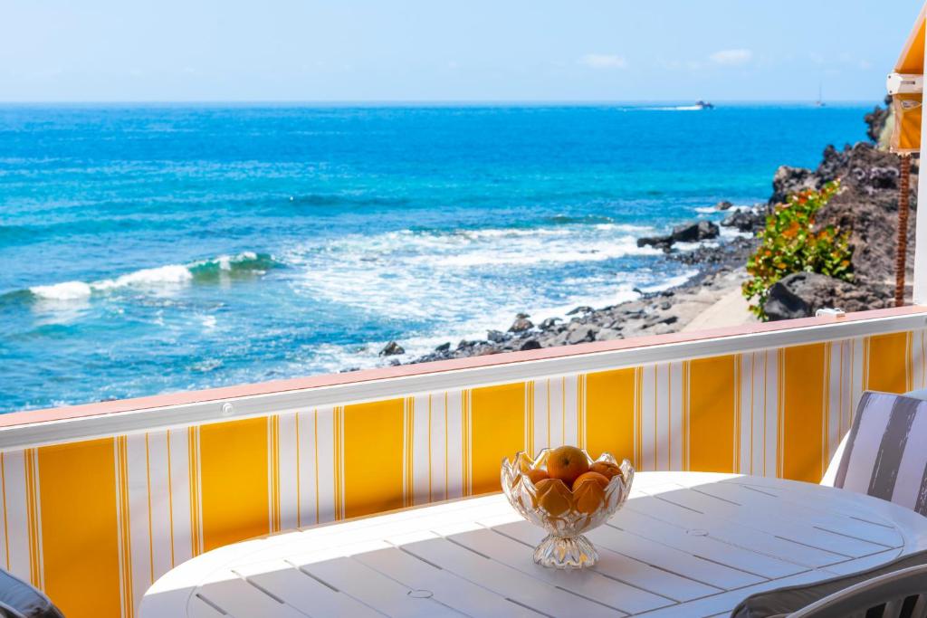 圣地亚哥港Neptuno Ocean View, Beach line with Pool的俯瞰大海的阳台的桌子上放着一碗水果