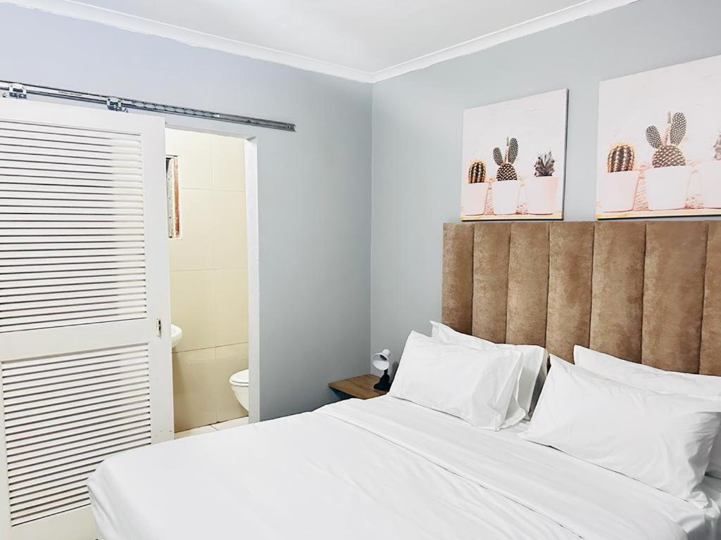 德班Decent Stay的卧室配有白色的床铺和白色的枕头