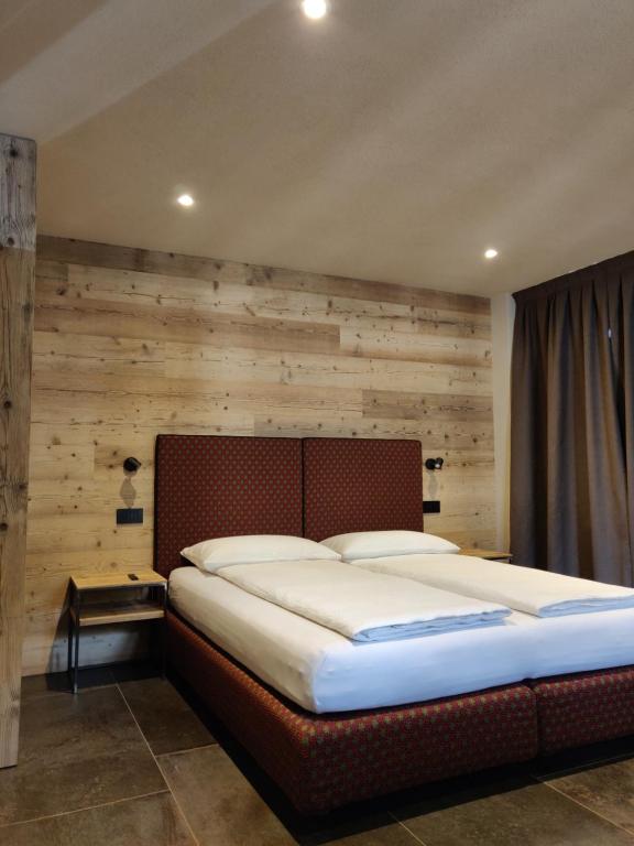 博尔米奥BAITA LARIX BORMIO的木墙客房内的一张大床