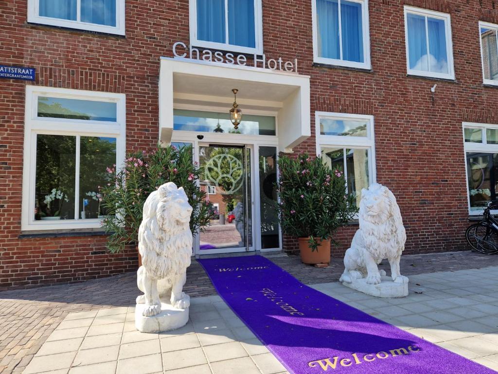 阿姆斯特丹Chassé Hotel Residency的两座白色的狗雕像,在一座建筑前