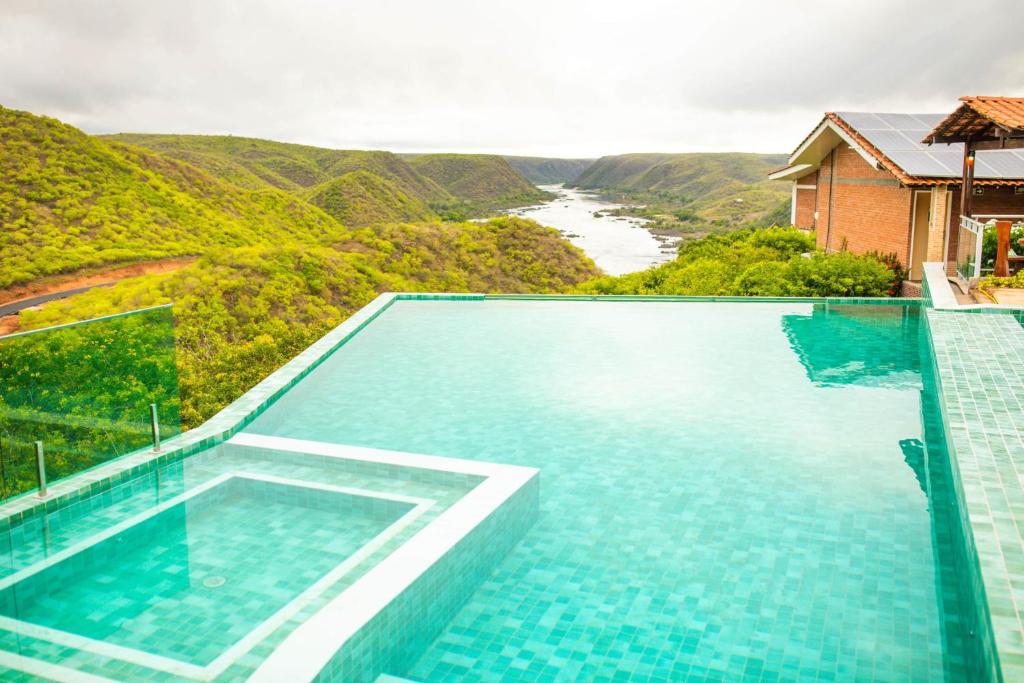 皮拉尼亚斯Pedra do Sino Hotel的享有河流和山脉景色的游泳池