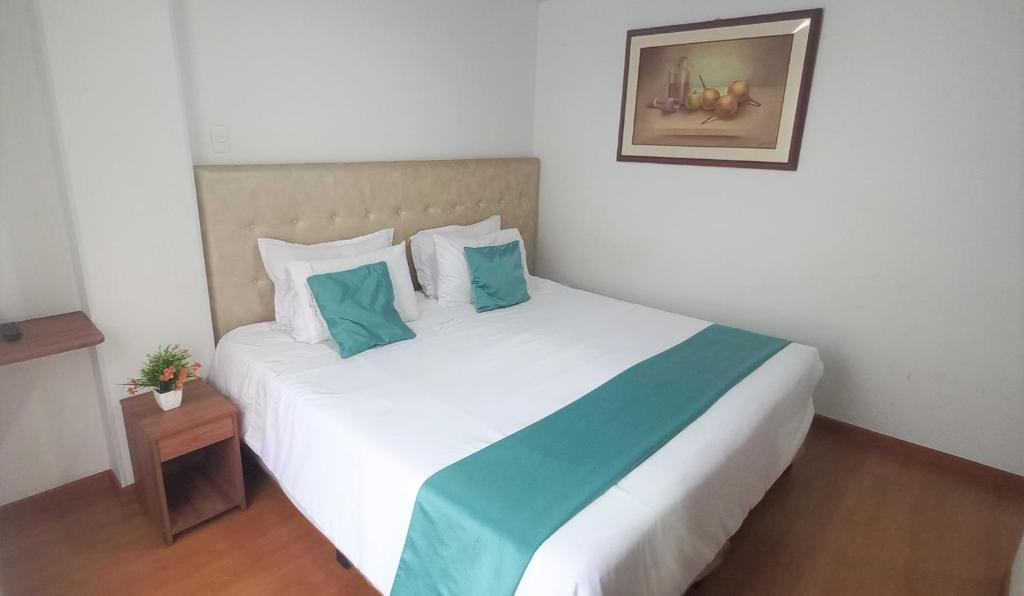 波哥大Hotel en Bogota - Fontana Di Trevi的卧室配有带蓝色枕头的大型白色床