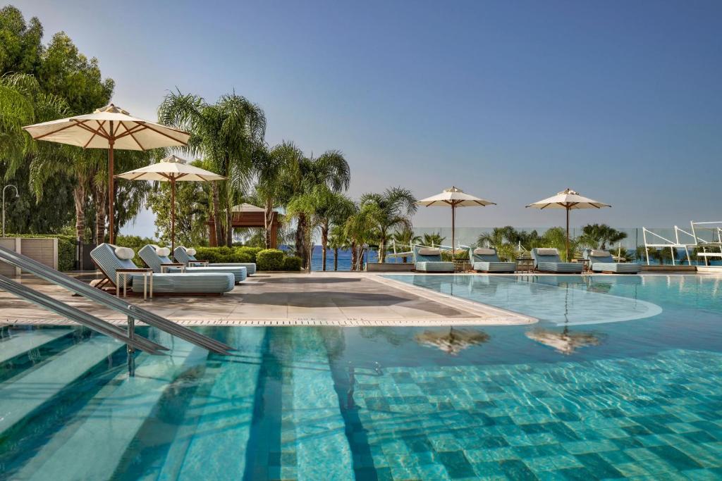 利马索尔Parklane, a Luxury Collection Resort & Spa, Limassol的一个带椅子和遮阳伞的大型游泳池