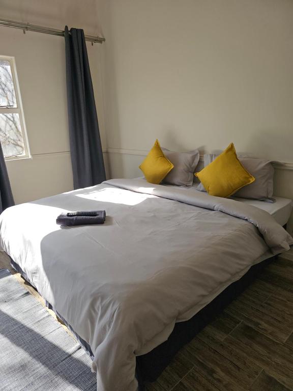 埃尔默洛Legends Lodge的一张带黄色枕头的床和遥控器