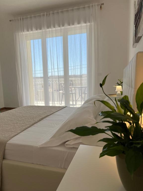 圣卡特琳娜迪纳德Domusvacanza Salento的白色的卧室设有床和大窗户
