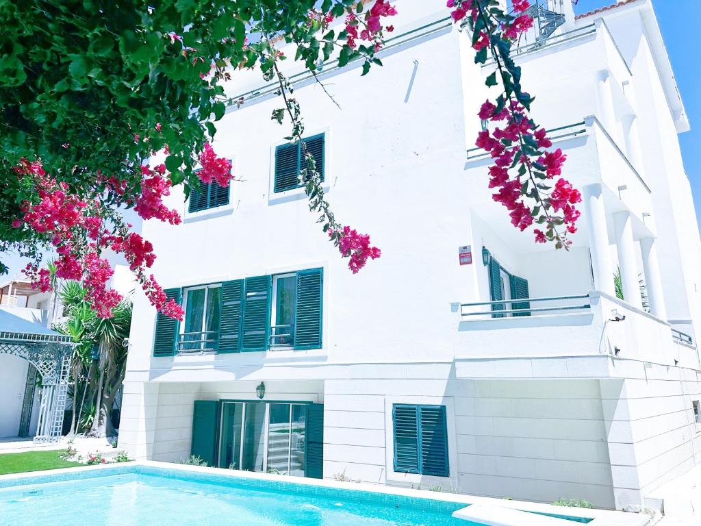 卡帕里卡海岸Yo-House的白色的建筑,设有游泳池和粉红色的鲜花