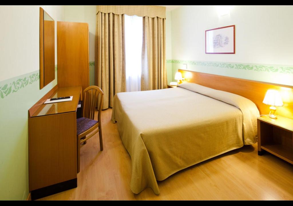 比萨特米纳斯广场酒店的酒店客房配有一张床、一张书桌和一台电视。