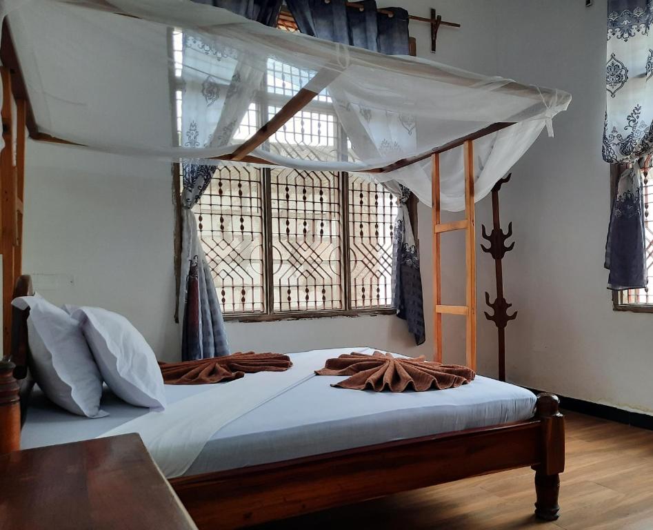 南威Kajificheni House的一间卧室设有天蓬床和窗户。
