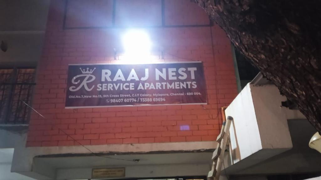 钦奈RAAJNEST SERVICE APARTMENTS的砖楼边的标志