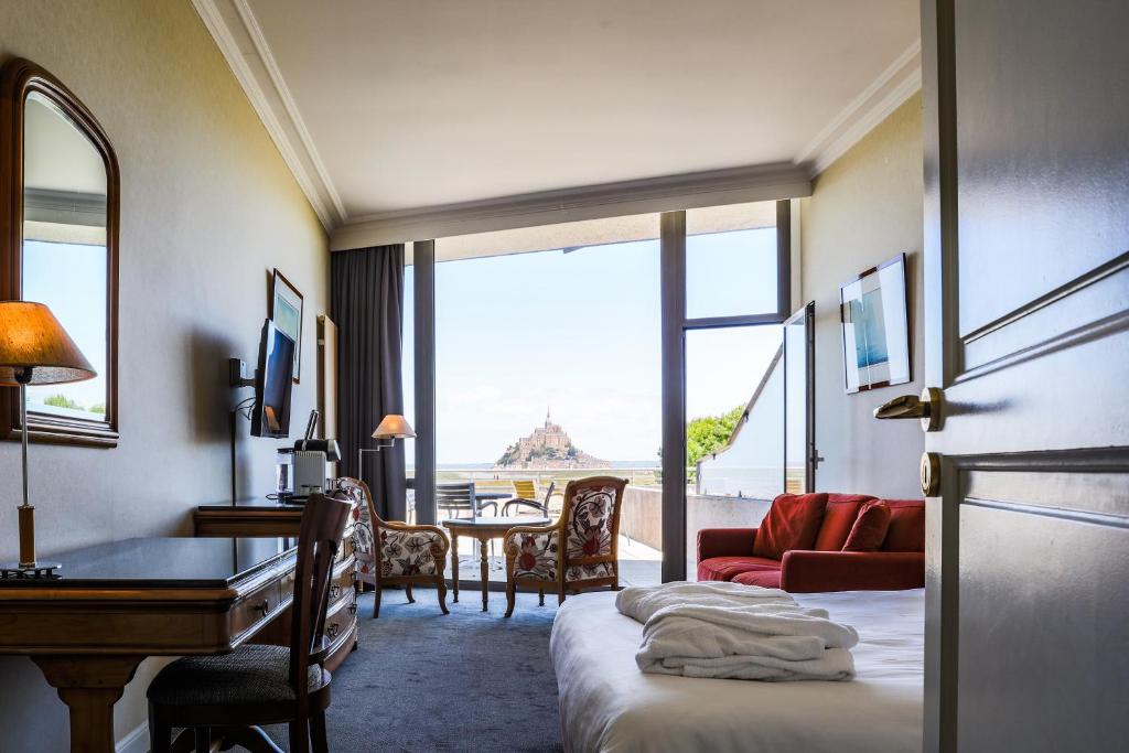 圣米歇尔山圣米歇尔驿站酒店的配有一张床、一张书桌和一扇窗户的酒店客房