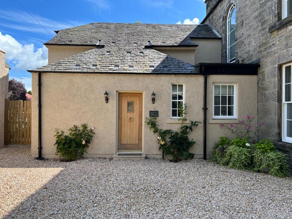 LoanheadQuaint self contained cottage near Edinburgh.的砂石车道上一扇棕色门的房子