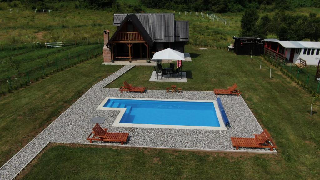 维舍格勒Vikendica sa bazenom MAGNUM的享有带椅子的游泳池和房屋的顶部景致