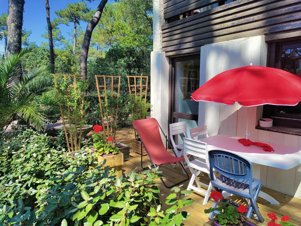 塞尼奥斯Appt Seignosse le Penon - plages commerces à pied的庭院配有桌椅和红色遮阳伞。