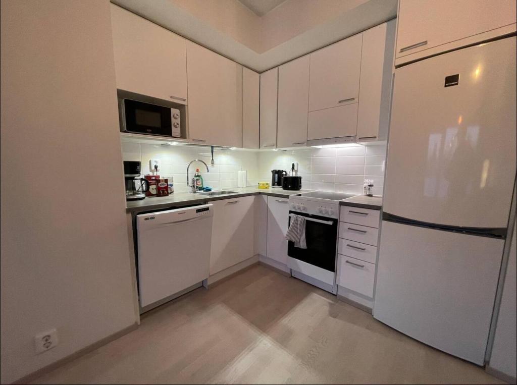 海门林纳Kaksio keskustassa ja rannan läheisyydessä的厨房配有白色橱柜和白色冰箱。