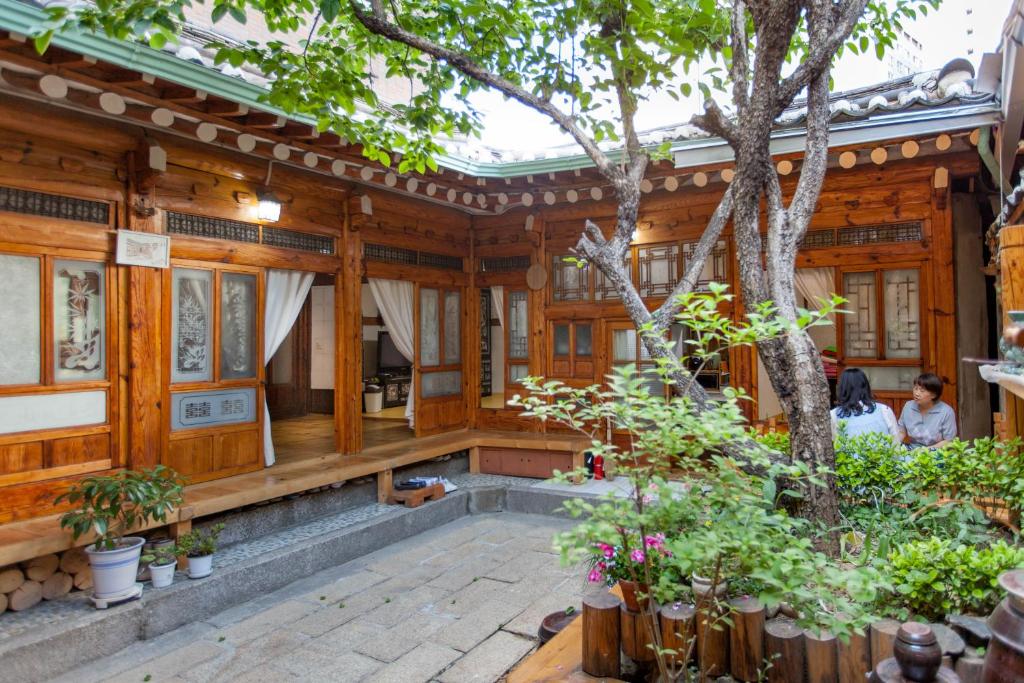 首尔Dongmyo Hanok Sihwadang - Private Korean Style House in the City Center with a Beautiful Garden的前面有一棵树的木屋