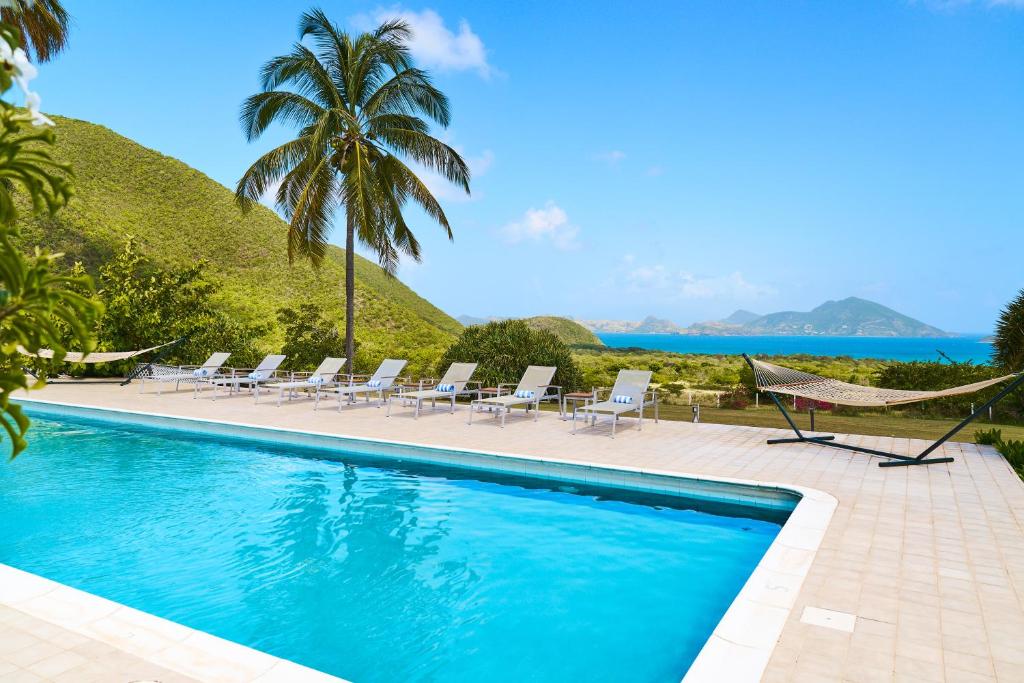 尼维斯Mount Nevis Hotel的一个带椅子的游泳池,享有海景