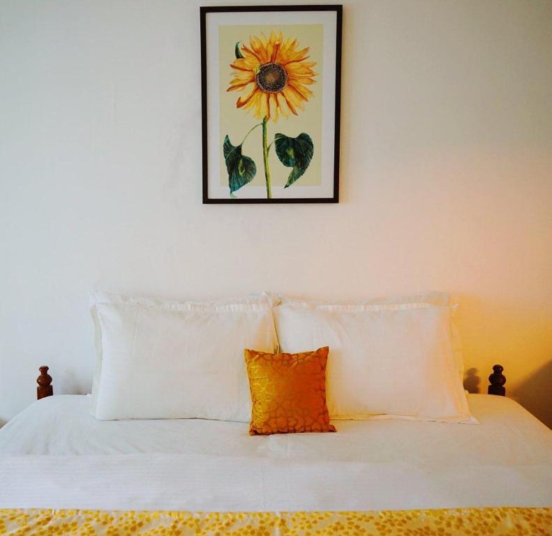 科钦Fortis Rooms的一张带白色枕头的床和一张向日葵的照片